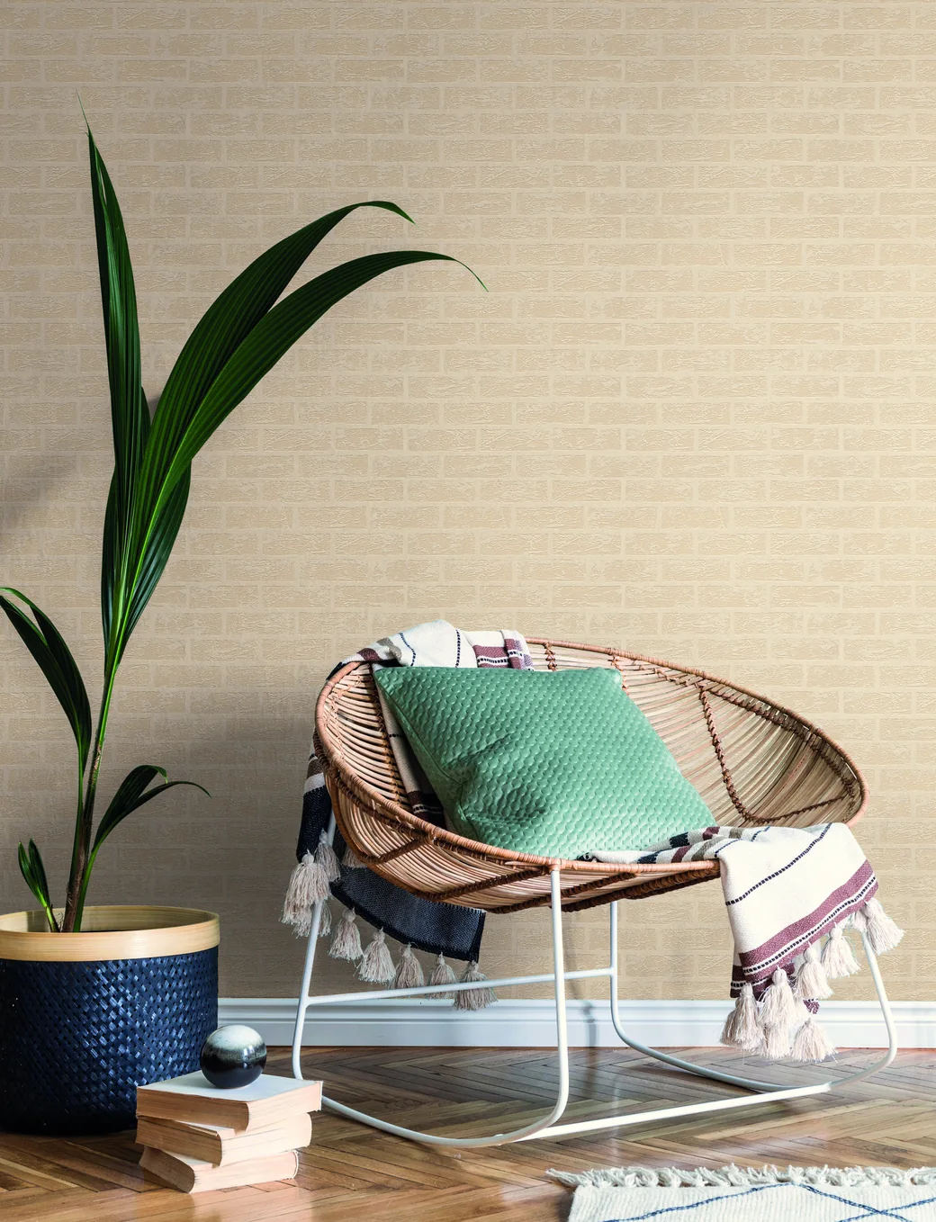 Papier peint Terra à base d’argile à effet brique dans des tons chaleureux, avec un fauteuil en rotin et une plante verte